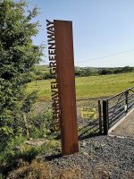 An artistic metal signpost with the words GLENRAVEL GREENWAY rising vertically